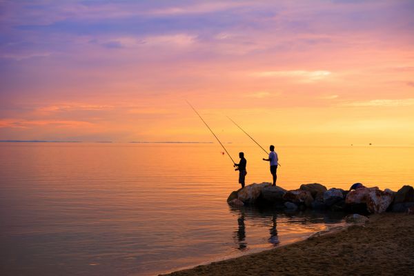 夕阳下在岸边钓鱼的两个人
