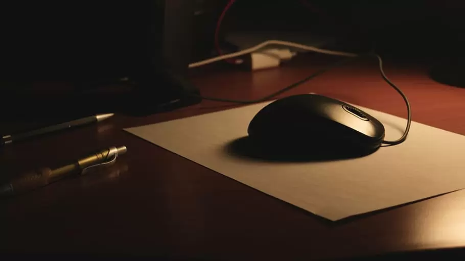 桌子上，一个黑色的鼠标放在鼠标垫上